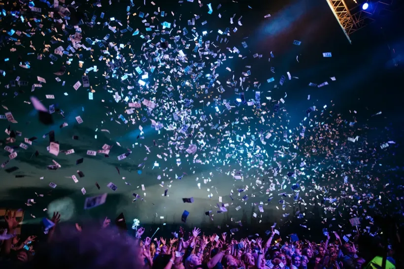 Crowd celebrating beneath blue lights at a live event